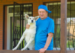 Senior man with mixed breed dog in a veranda