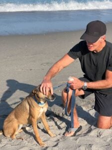 Dave puts sunscreen on his dog, Sasha at the beach