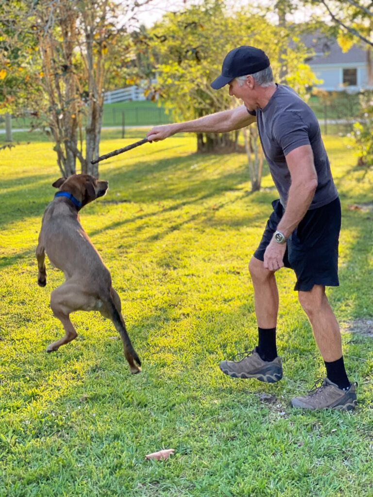 Dave and his dog, Sasha, playing with a stick on their farm