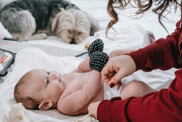 Dog ate a diaper: Mom changing a baby's diaper with a dog nearby